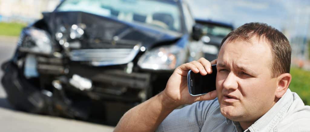Adult upset driver man discussing on mobile phone in front of automobile crash car collision accident in city road